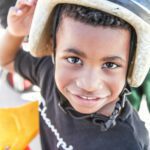 Photo of young African American boy wearing a helmet. Join flight to help homeless children.