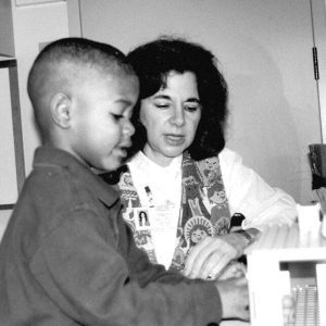 black and white photo of teacher teaching student while sitting at a table almost 35 years ago